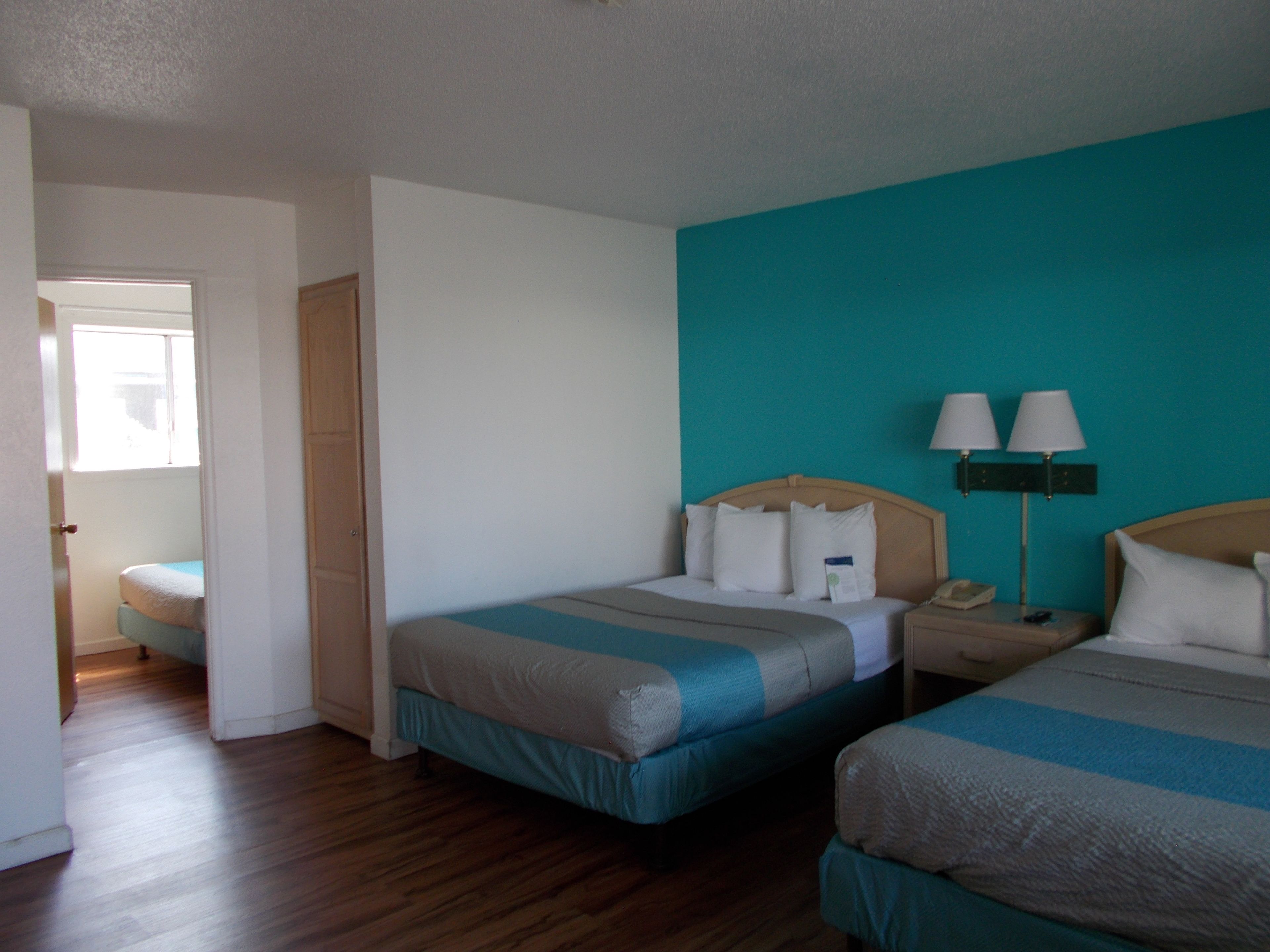 Una habitación de hotel con dos camas, una mesita de noche, una lámpara y una ventana.