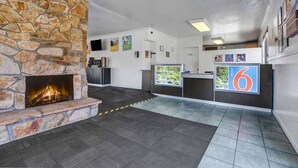 A lobby with a stone fireplace, a reception desk, and a large number '6' sign. - Motel 6 Fort Bragg, CA (Fort Bragg)
