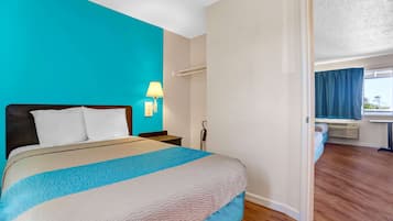 A hotel room with a bed, a nightstand, a lamp, and a window with curtains.
