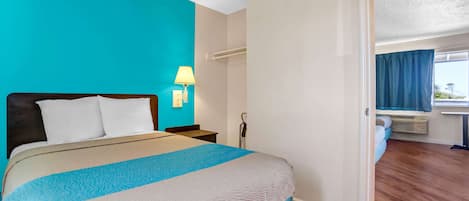 A hotel room with a bed, a nightstand, a lamp, and a window with curtains.