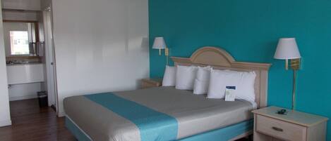 A hotel room with a bed, nightstands, a lamp, and a view of the bathroom.