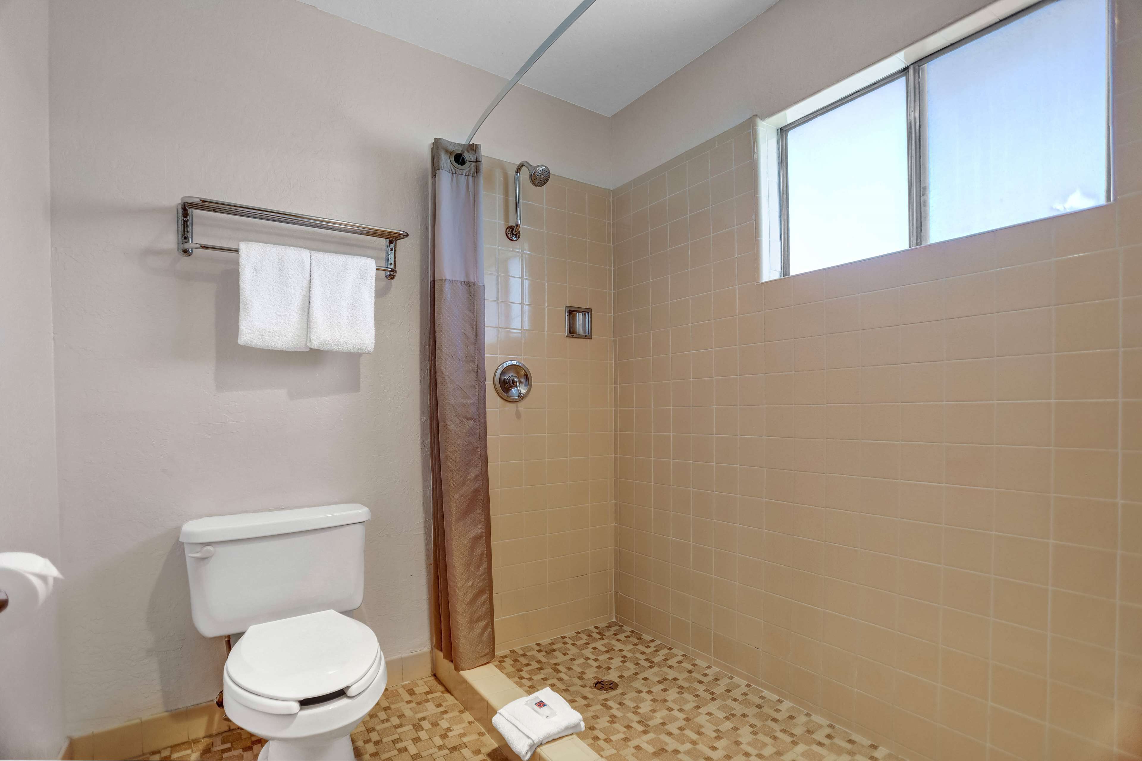 Un baño con inodoro, ducha con puerta de cristal y ventana que proporciona luz natural.