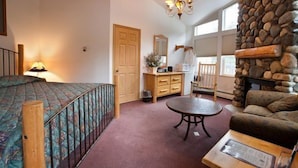 A cozy living room with a stone fireplace, a round table, and a comfortable sofa. - Harborview Inn (Seward)