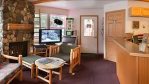 A cozy lobby with a stone fireplace, wooden furniture, a reception desk, and a fish wall decoration. - Harborview Inn (Seward)