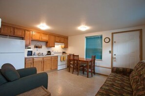 A compact kitchen with wooden cabinets, a dining table, and a sofa.