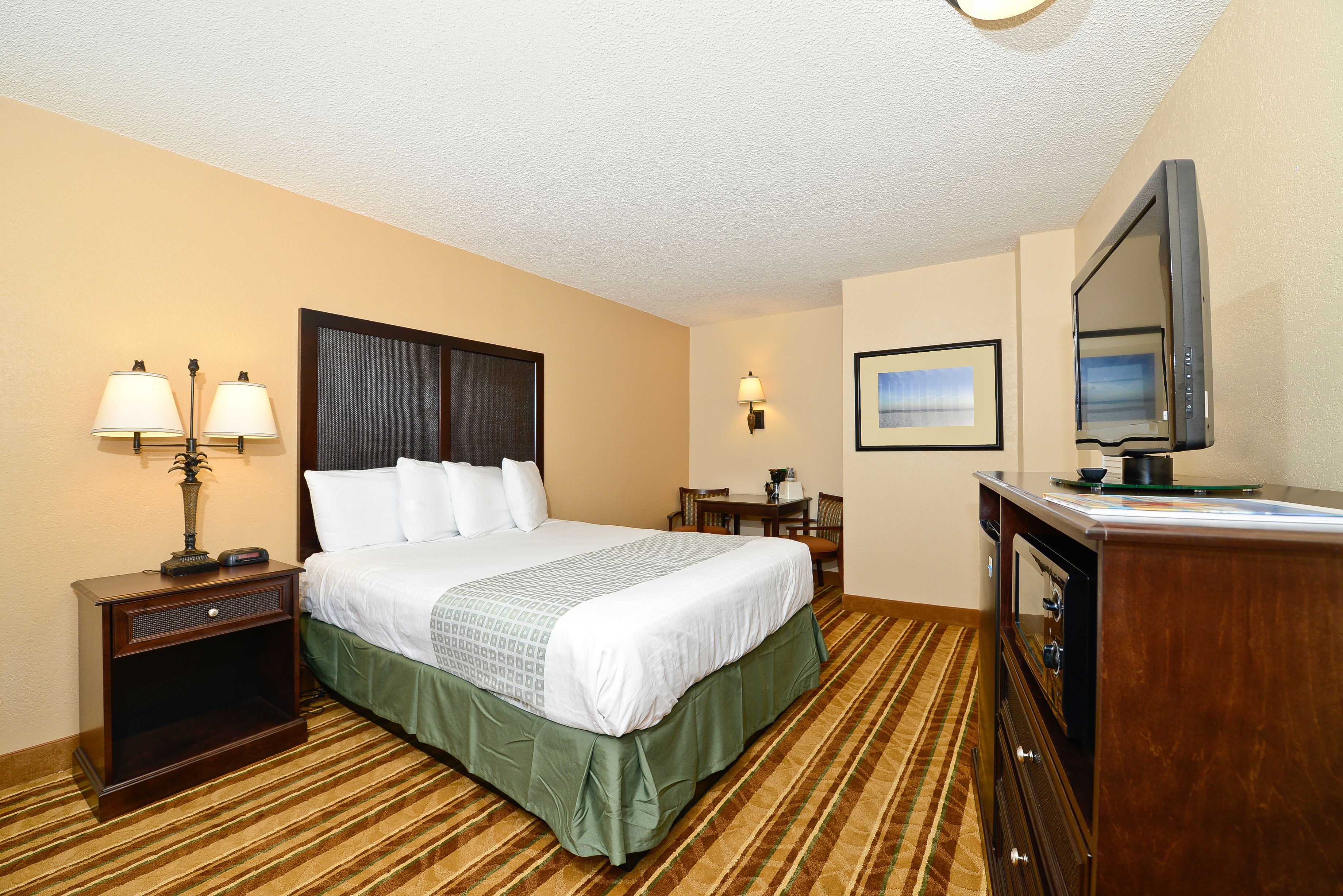 A hotel room with a bed, bedside lamps, a television, a desk, and a chair.