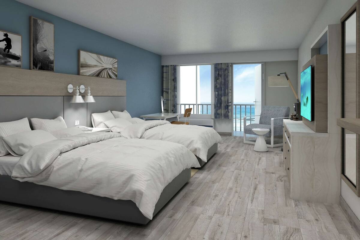 A modern hotel room with a large bed, a desk, a chair, a TV, and a balcony with a view.