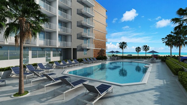 A modern hotel with a pool, sun loungers, and a view of the beach.