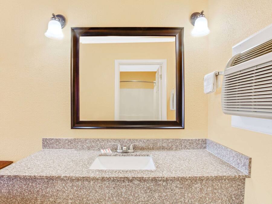 Un baño con lavamanos de encimera de granito, un espejo grande y un perchero para toallas.