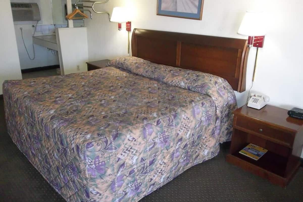 A hotel room with a bed, bedside tables, a mirror, and a telephone.