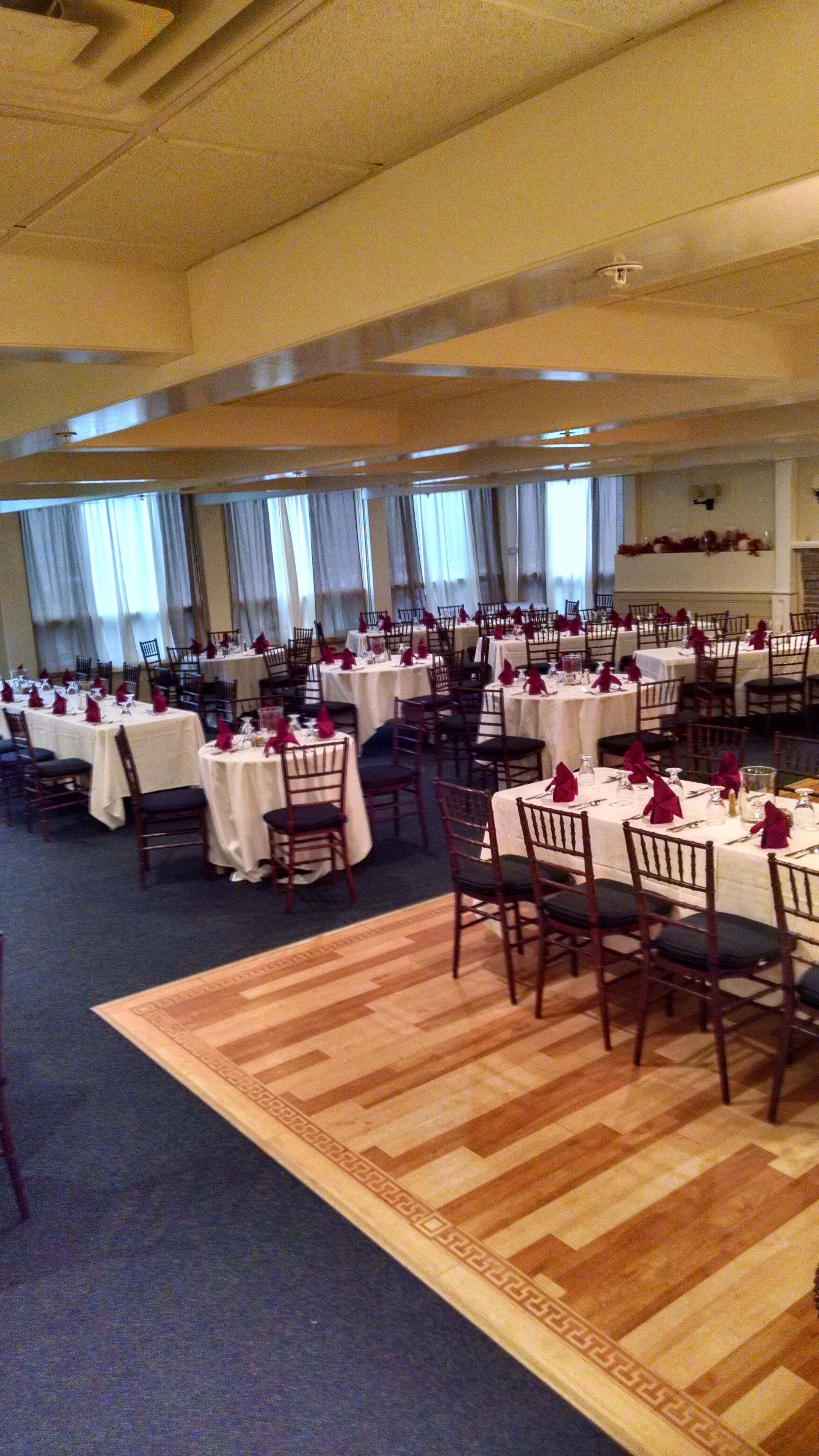 A banquet hall with multiple round tables set for dining, each with chairs and table settings.