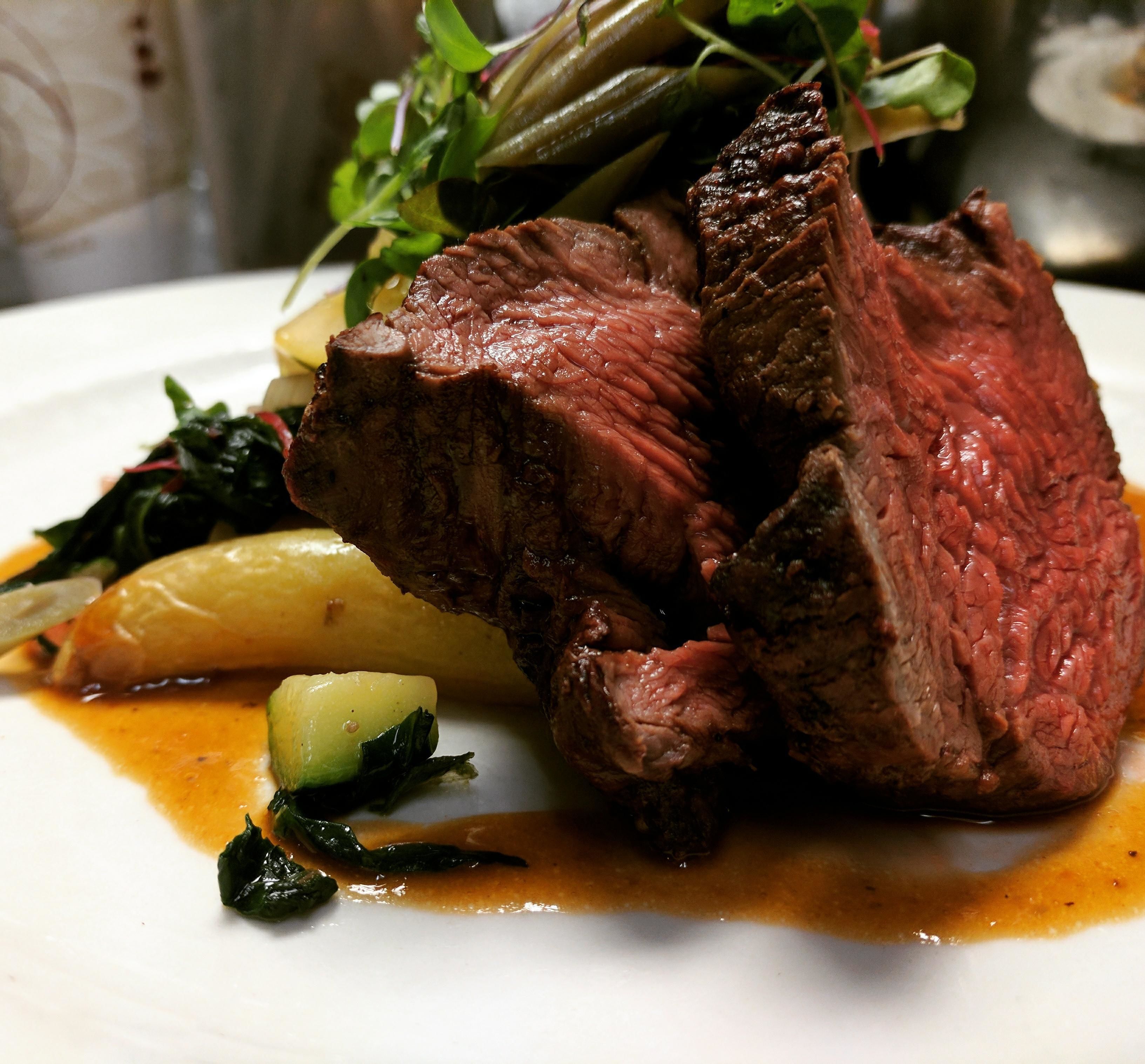 A plate of food with steak, vegetables, and sauce.
