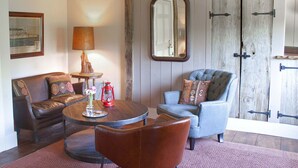 Un salon chaleureux avec un canapé en cuir marron, un fauteuil bleu, une table basse en bois et une lanterne rouge.