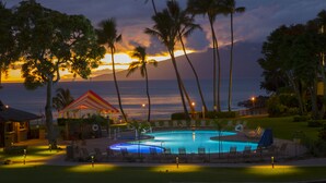 A pool area with lounge chairs, a cabana, and palm trees at sunset. - Napili Kai Beach Resort (Lahaina)