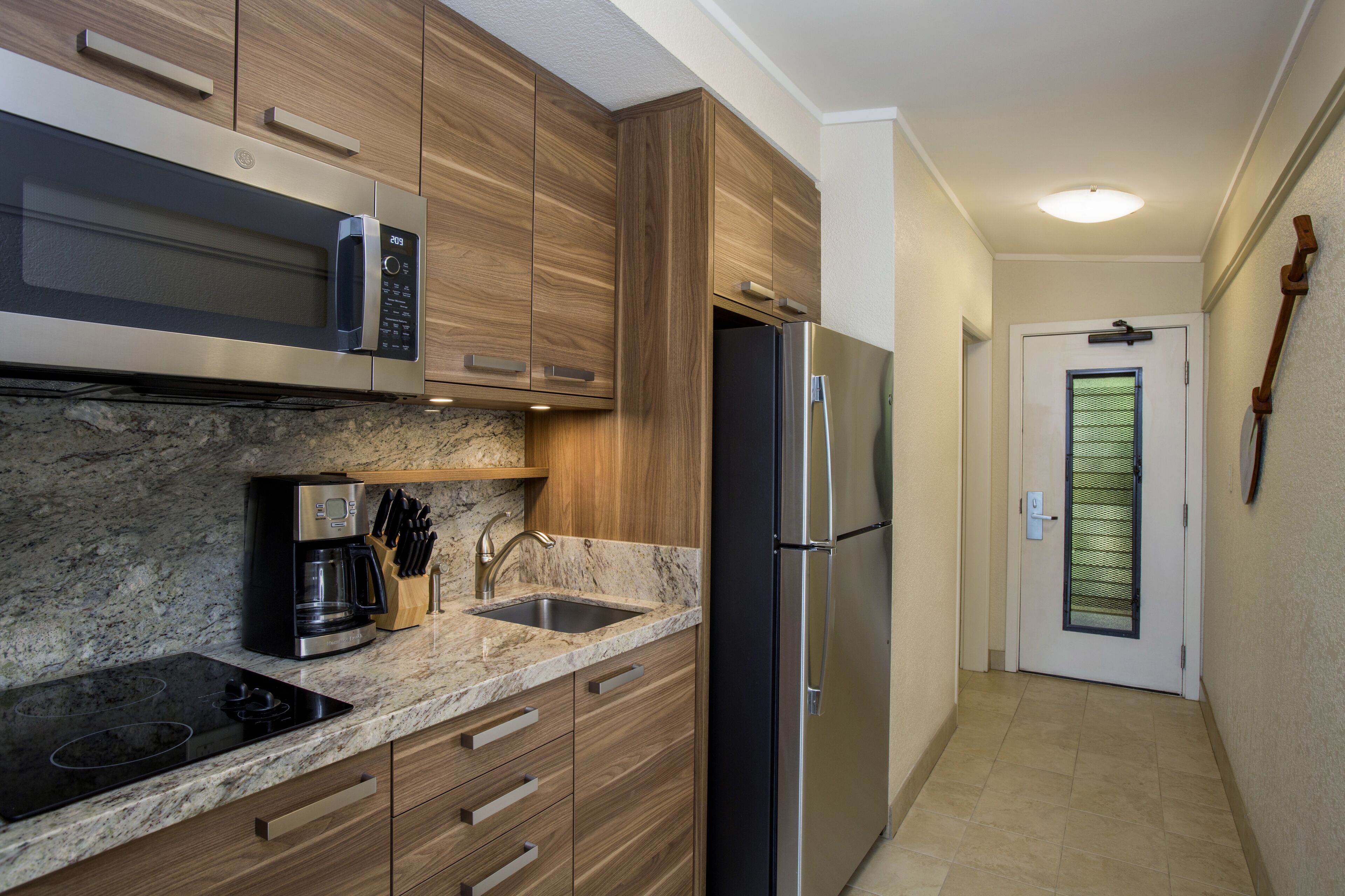 A modern kitchen with a built-in microwave, coffee maker, and stainless steel refrigerator.