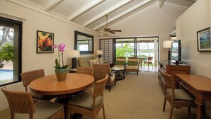 A spacious living area with a high ceiling, wicker furniture, a round dining table, and a television. - Napili Kai Beach Resort (Lahaina)