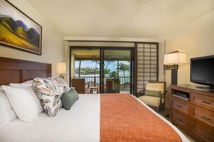 Habitación de hotel con cama, televisión, escritorio y vista al océano.