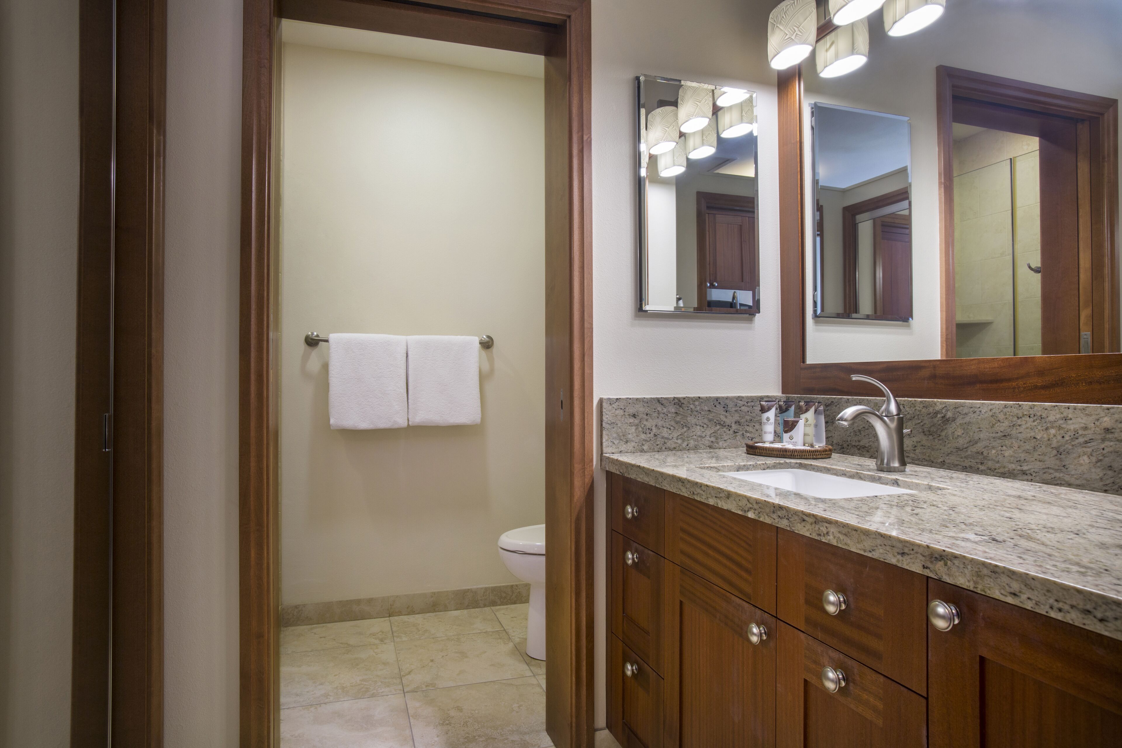 Un baño con lavabo, espejo y armarios de madera.