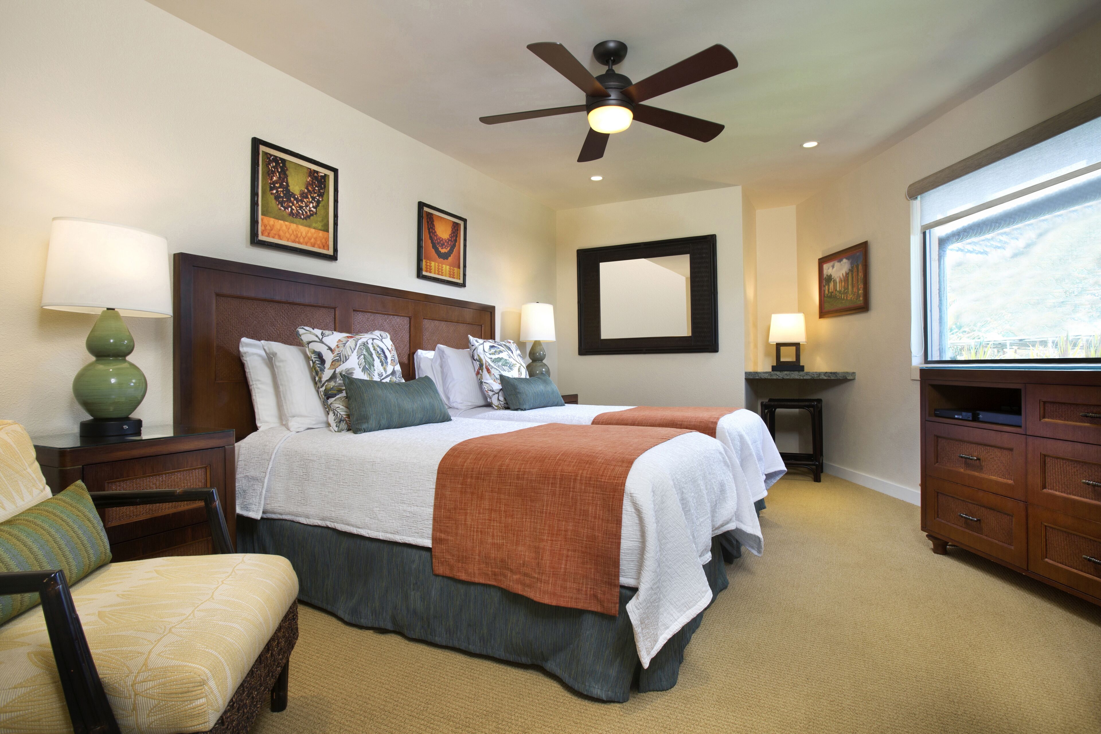 A hotel room with a large bed, two bedside tables, a chair, a wardrobe, a ceiling fan, and a window with a view.