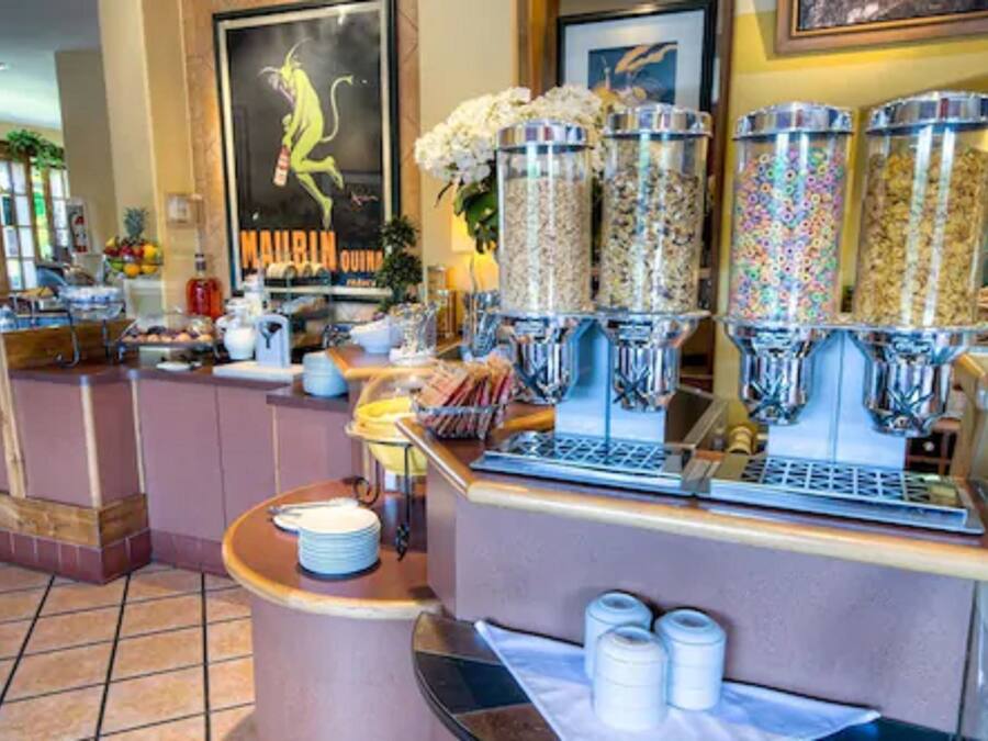Un área de bufé con varios dispensadores de alimentos, una máquina de café y una variedad de platos en la barra.