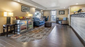 A hotel lobby with a seating area, a refrigerator with beverages, and a clock on the wall. - Comfort Inn Troutdale - Portland East (Troutdale)