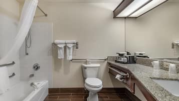 Uma casa de banho moderna com sanita branca, banheira com cortina de chuveiro, toucador com bancada e porta-toalhas.
