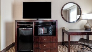 A hotel room with a flat-screen TV, a microwave, a small refrigerator, a desk with a lamp, and a mirror. - Comfort Inn Troutdale - Portland East (Troutdale)
