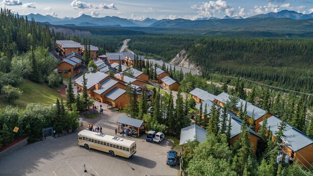 A lodge with multiple cabins, a bus, and a mountainous backdrop.