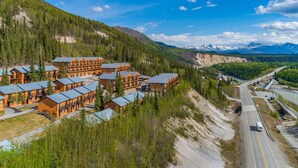 A lodge with multiple wooden buildings, a road, and a mountainous backdrop.