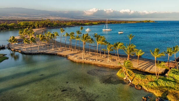 A coastal area with a clear view of the sea, a small island with palm trees, and boats in the distance. - Vista Waikoloa (Waikoloa)