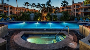 A swimming pool with a hot tub, surrounded by palm trees and lounge chairs, with a hotel building in the background. - Vista Waikoloa (Waikoloa)