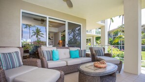 A sunlit outdoor seating area with wicker furniture and a ceiling fan. - Vista Waikoloa (Waikoloa)