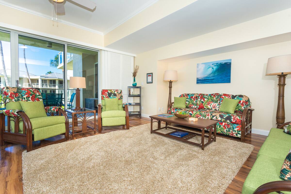 A living room with a large window, a sofa, two chairs, a coffee table, and a lamp.