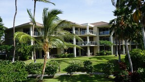 A multi-story hotel with balconies, surrounded by well-maintained lawns and palm trees. - Vista Waikoloa (Waikoloa)