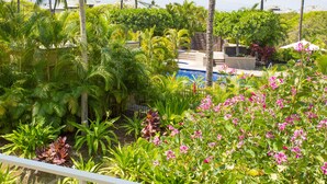 A lush garden with a pool, palm trees, and various tropical plants. - Vista Waikoloa (Waikoloa)