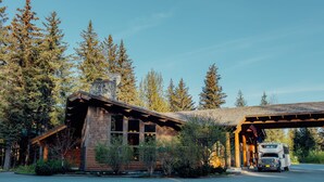 A rustic cabin with a covered porch and a parked RV. - Seward Windsong Lodge (Seward)
