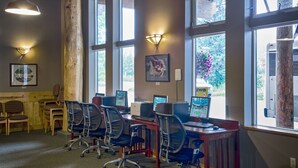 A computer lab with multiple workstations, chairs, and large windows providing natural light. - Seward Windsong Lodge (Seward)