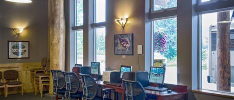 A computer lab with multiple workstations, chairs, and large windows providing natural light.
