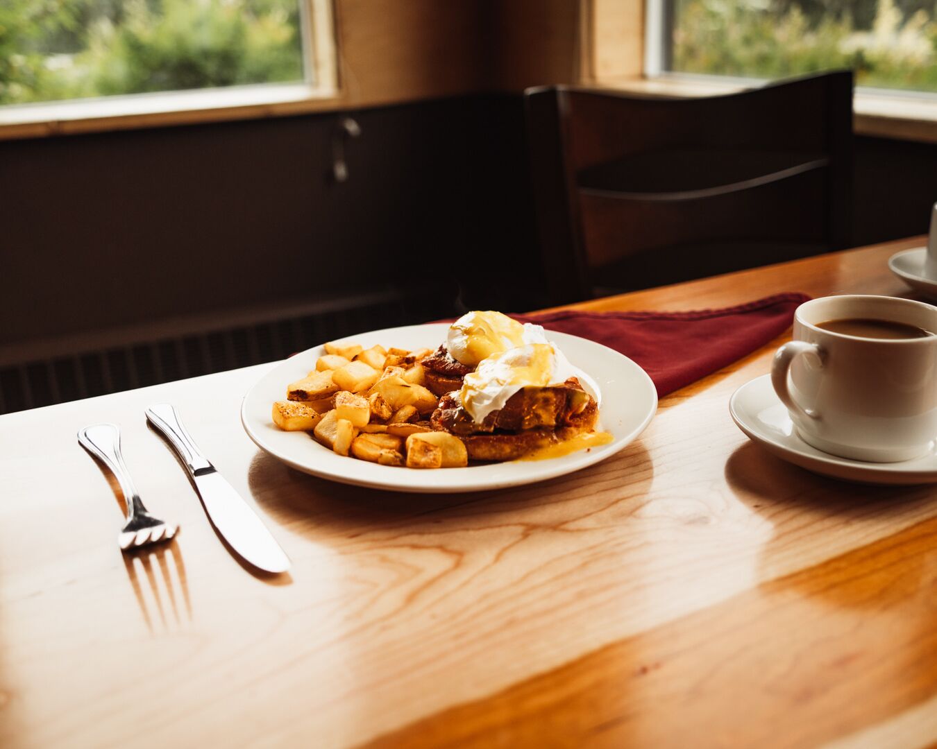A plate of food with a cup of coffee on a table by a window.