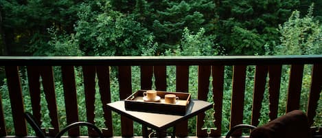 A balcony with a table set for two, featuring a tray with cups and saucers.