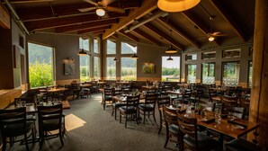 A spacious restaurant with high ceilings, large windows, and multiple dining tables and chairs. - Seward Windsong Lodge (Seward)