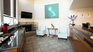 Una sala de estar moderna con chimenea, dos sillones estampados, un televisor de pantalla plana y un cuadro abstracto grande en la pared.