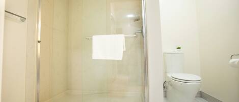 Un baño moderno con ducha de vidrio, inodoro y lavamanos.