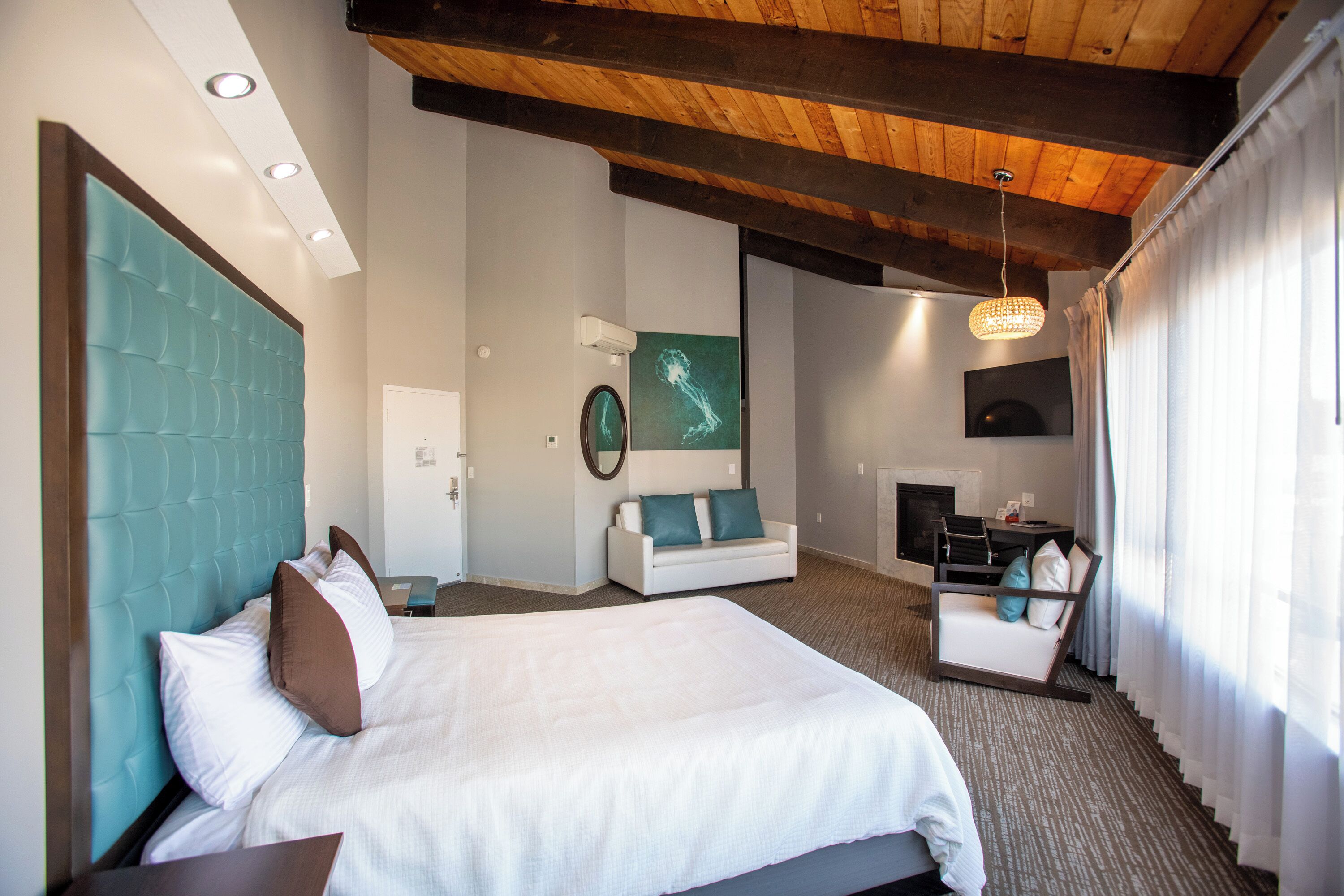 A modern hotel room with a large bed, a seating area, and a fireplace.