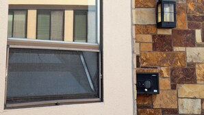 Un edificio con fachada de piedra, un ventanal grande y un cartel que indica una oficina.