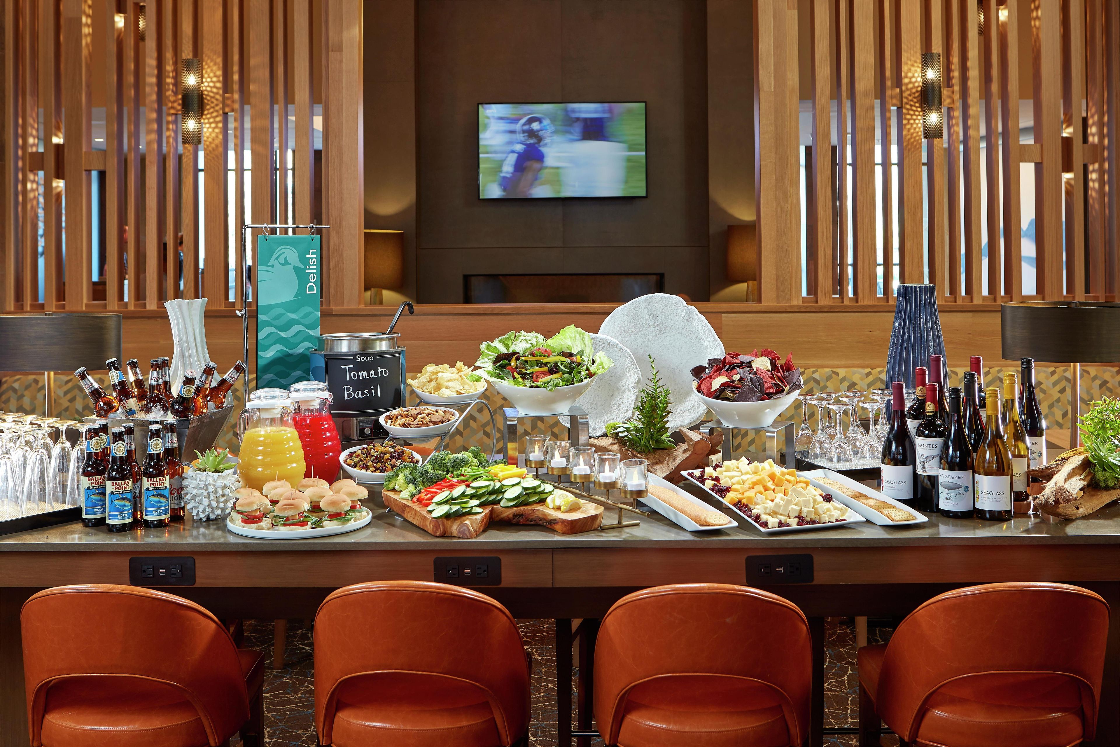 A buffet table with various food items, a television in the background, and a wooden partition.