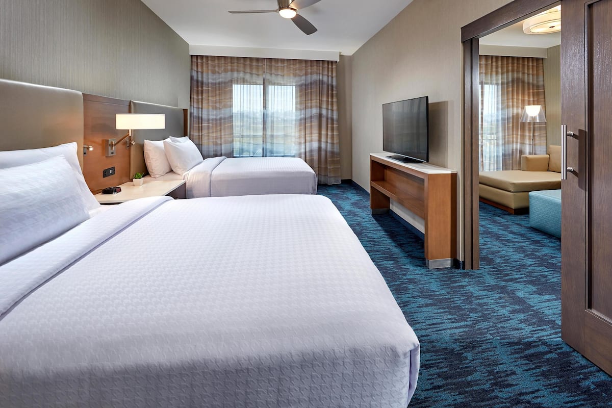 Habitación de hotel con dos camas, televisión, escritorio y zona de estar.