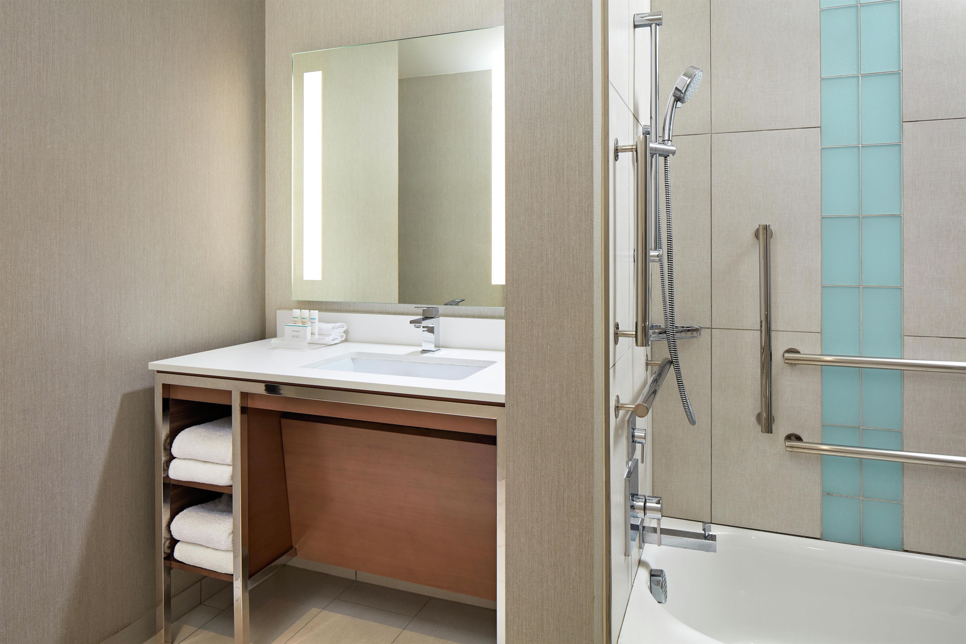 A modern bathroom with a sink, mirror, and shower.
