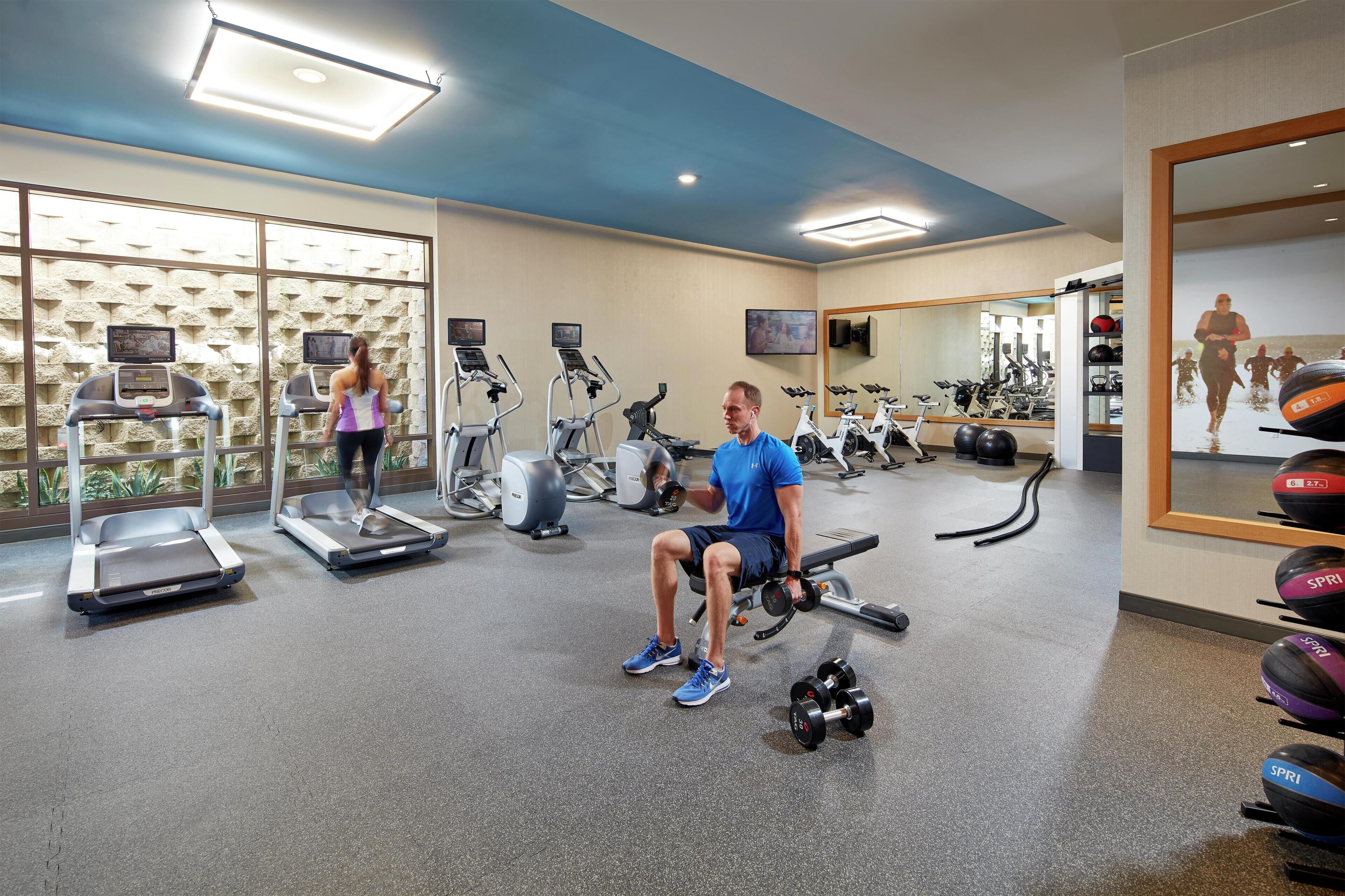 A gym with treadmills, elliptical machines, and a bench press area.