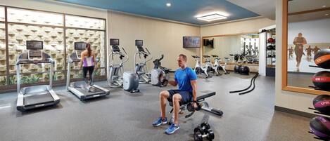 A gym with treadmills, elliptical machines, and a bench press area.